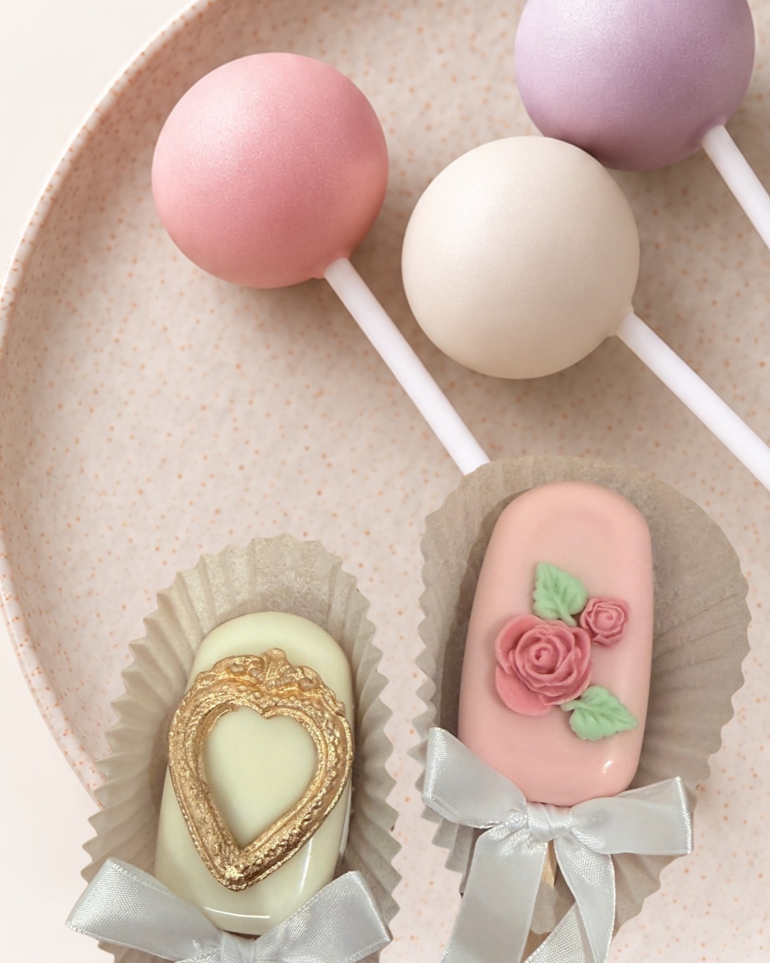 Rosa, weisse und lila Cake Pops und zwei Cakesicles mit Schleifen