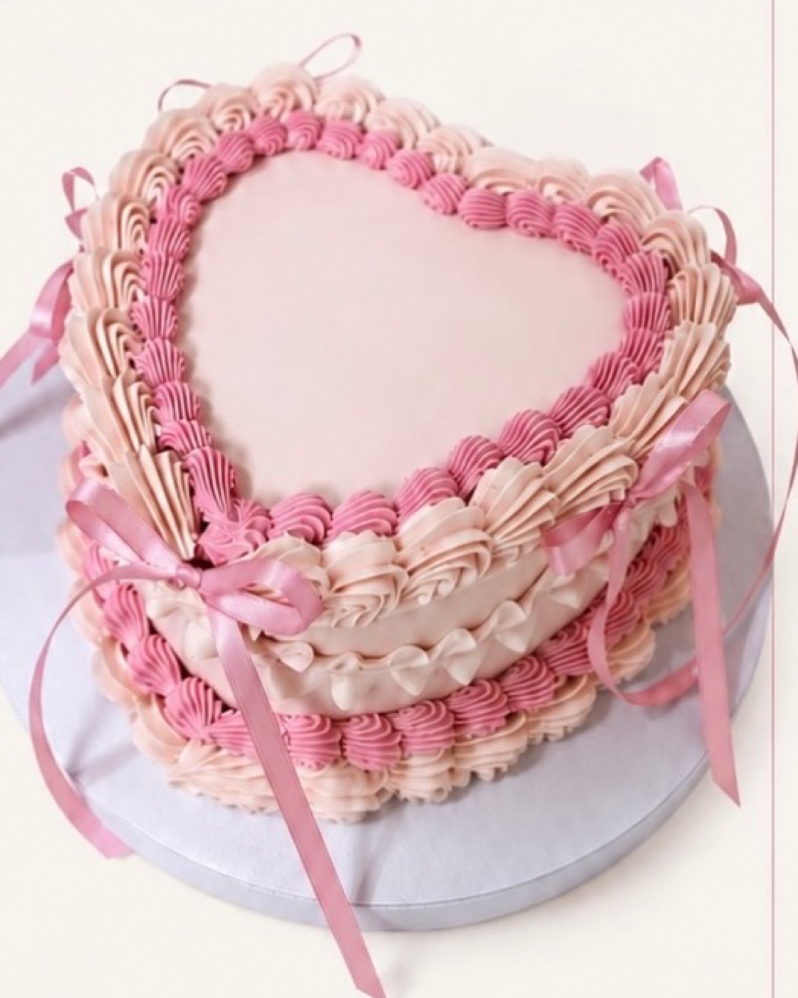 Herzförmige Mini-Torte in Rosa mit Buttercreme-Rüschen und Schleifen